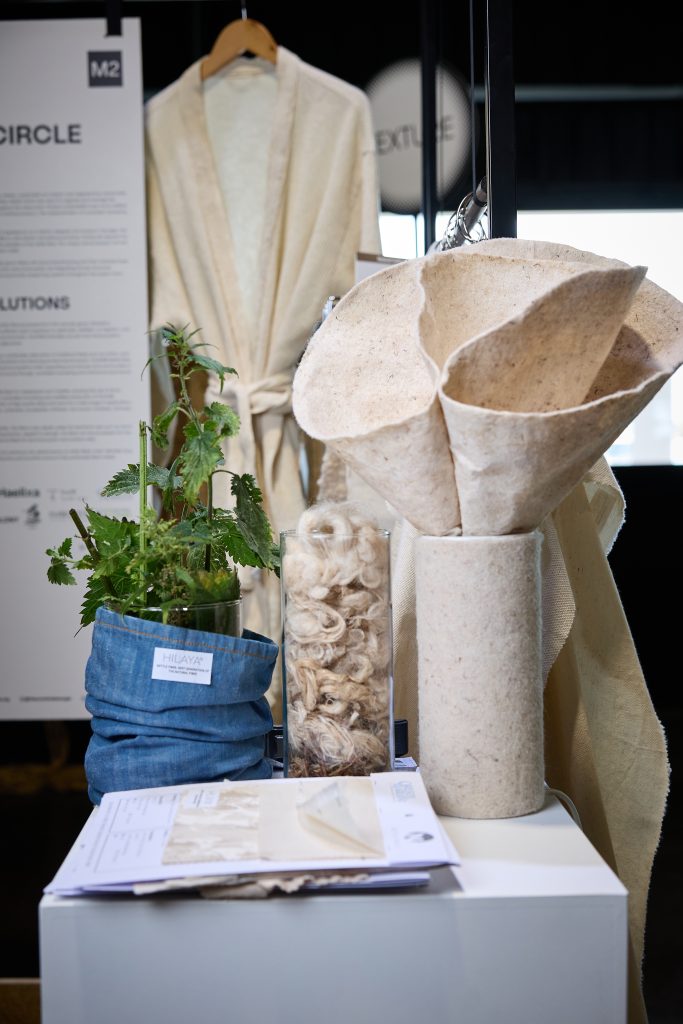 Exhibit of nettle plant, raw fibers, and sustainable textiles by Nettle Circle with Haelixa DNA traceability